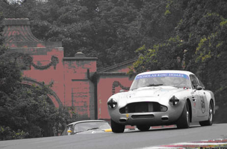 A white Aston Martin races over the hill.